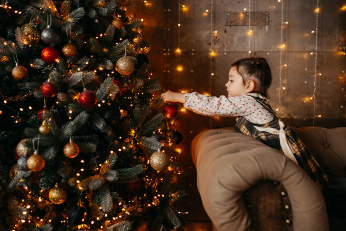 Little girl decorating a christmas tree at home.
