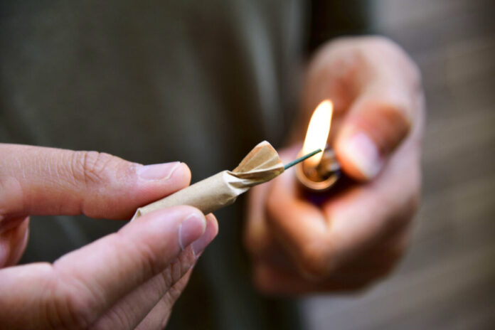 young man lighting a firecracker