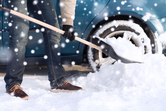 closeup of man digging snow with shovel near car