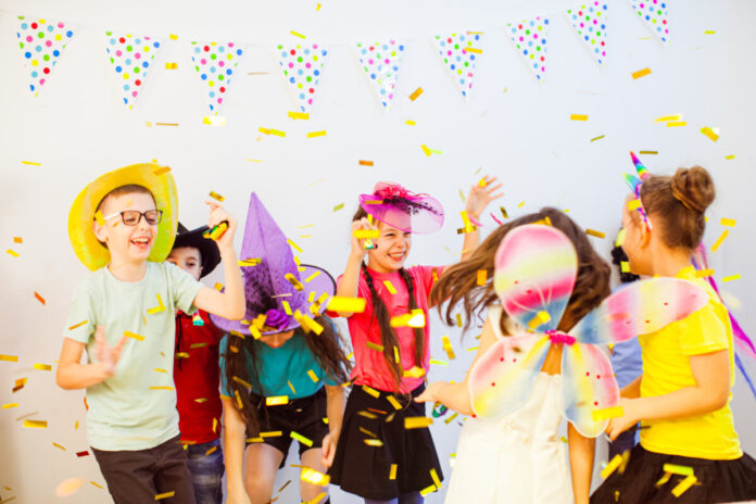 Excited happy children dancing at birthday party. Kids enjoying glitter confetti