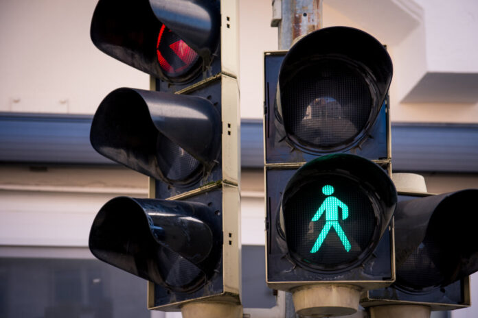 a traffic light with pedestrian signs in a city