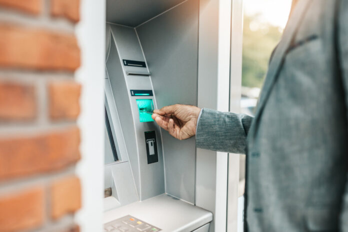A senior man withdraws money from an automated teller machine (ATM).