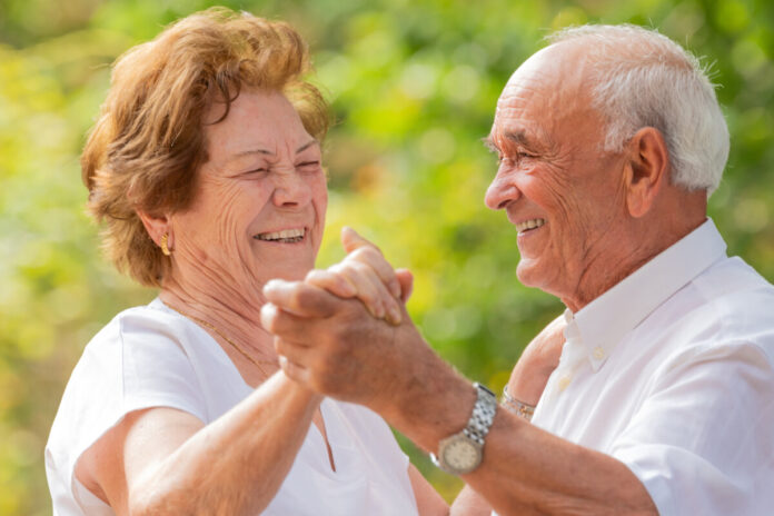smiling senior couple dancing happily outdoors