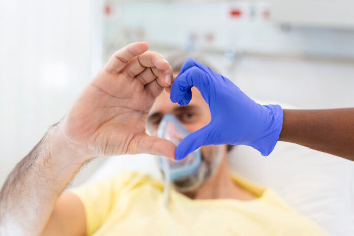 Doctor and patient make finger heart shape wearing blue disposable latex glove, rubber glove for professional medical safety and hygiene protection from Coronavirus disease COVID-19 and surgery