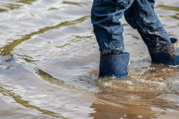 Kind mit blauer Hose und blauen Gummistiefeln watet nach einer