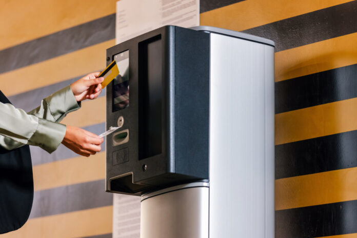 Businesswoman paying for parking ticket at car parking payment machine using credit card.
