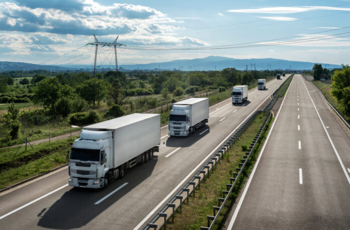 Transportation trucks passing by on a country highway under a be
