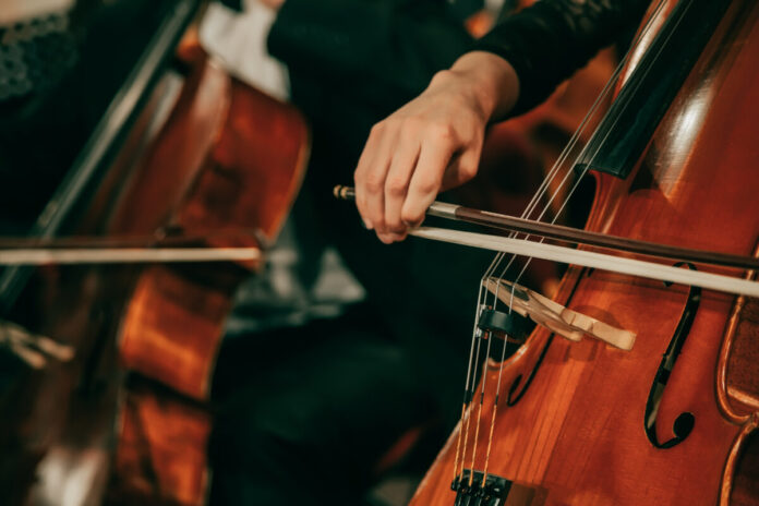 Symphony orchestra on stage, hands playing cello