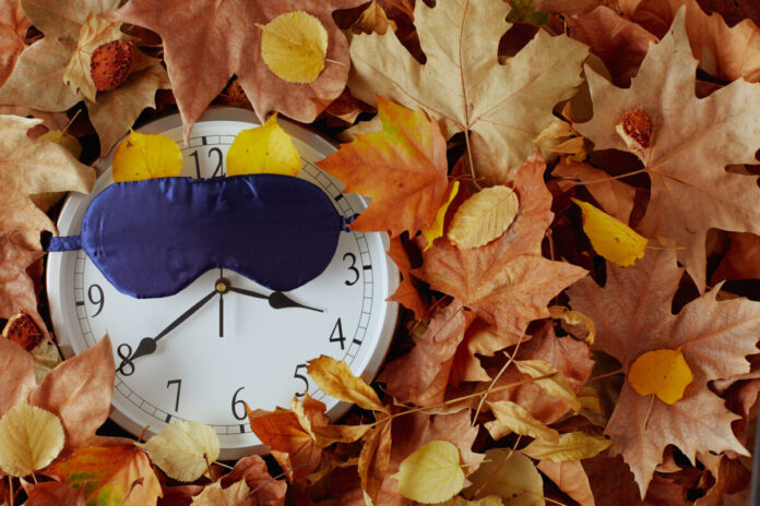 autumn background with clock, sleeping mask and leaves